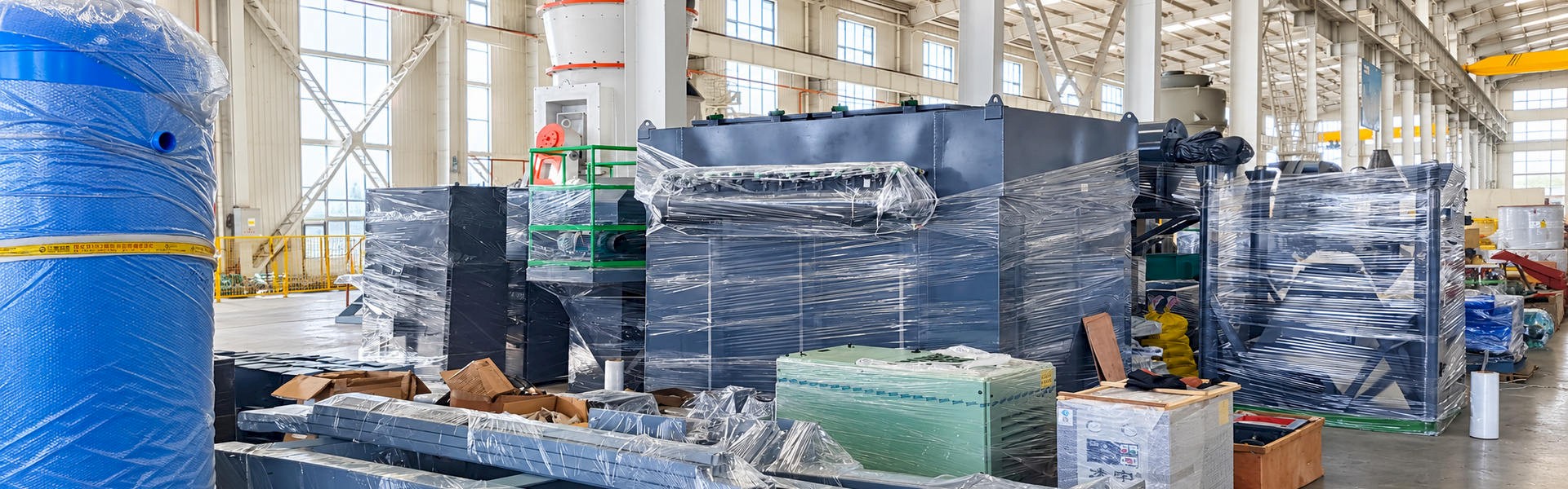 Industrial processing equipment and steel components in protective wrapping inside a manufacturing facility.
