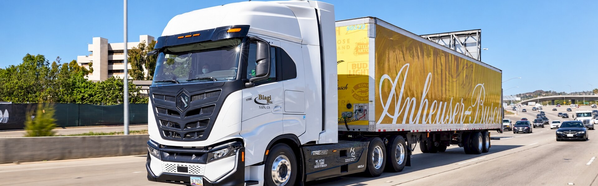 Nikola Tre fuel-cell truck hauling an Anheuser-Busch trailer along a busy highway.
