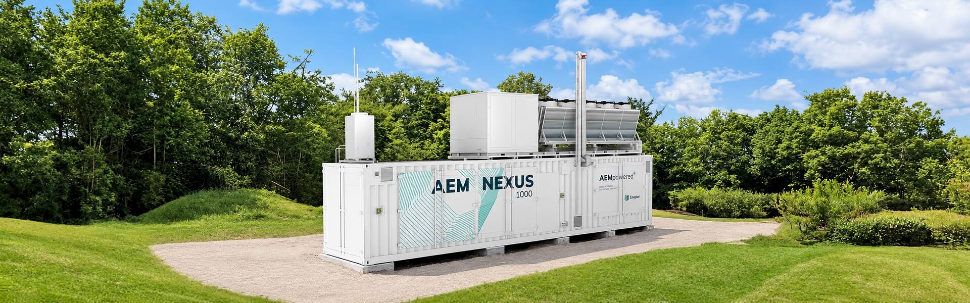 Enapter AEM Nexus 1000 containerized hydrogen electrolyser with rooftop cooling equipment, surrounded by trees and grass.