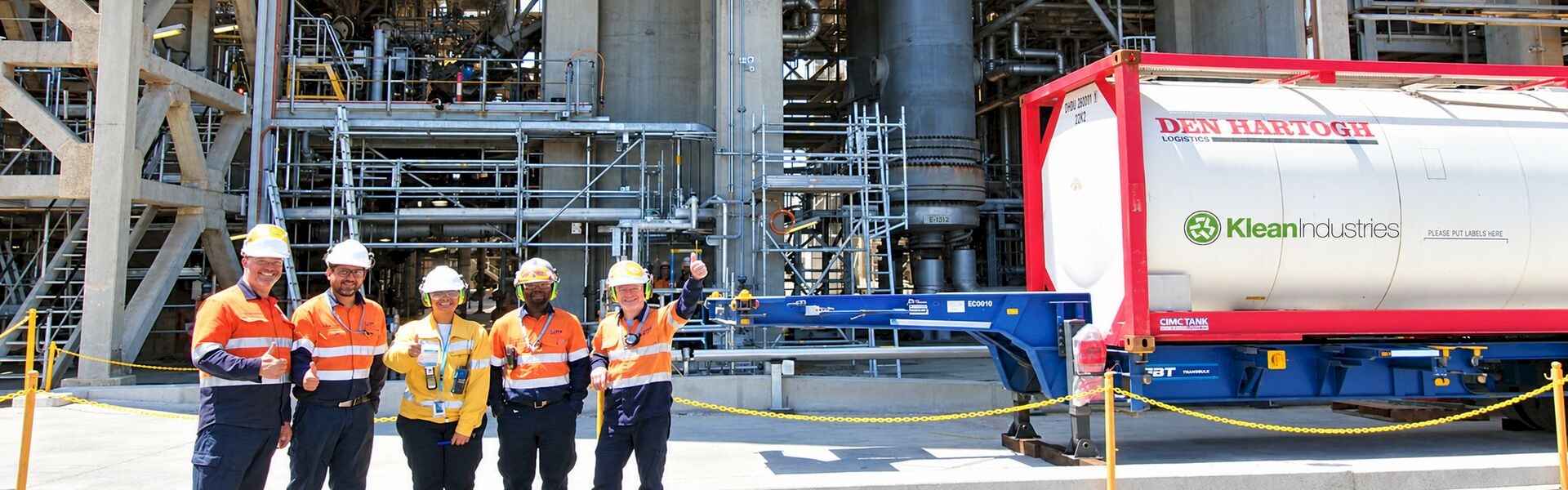 Five people in safety clothing beside a Klean Industries-branded tank container at Viva Energy’s refinery.