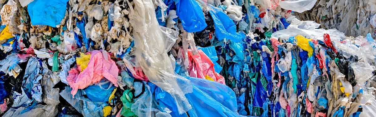 Close-up of compressed mixed waste-plastic film in blue, white, pink and yellow, collected for recycling.